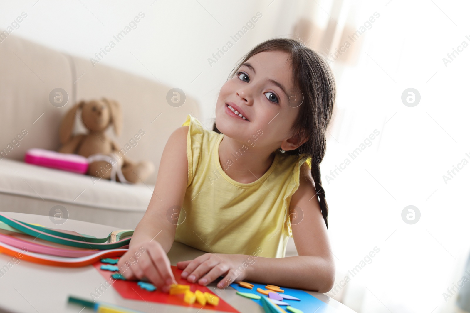 Photo of Little girl quilling at table indoors. Creative hobby