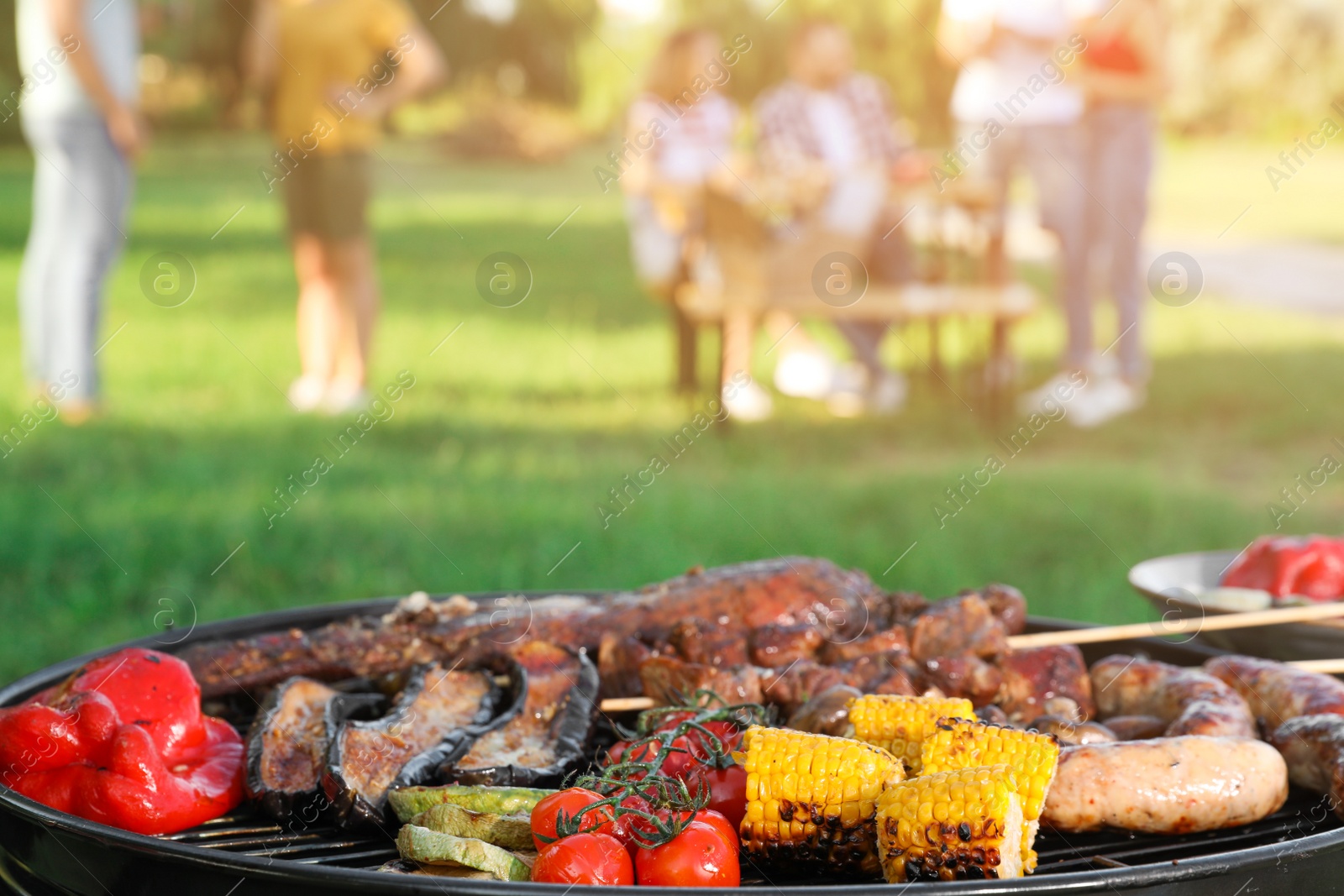 Photo of Group of friends having party outdoors, focus on barbecue grill with food