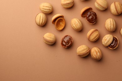 Photo of Homemade walnut shaped cookies with boiled condensed milk on pale brown background, flat lay. Space for text