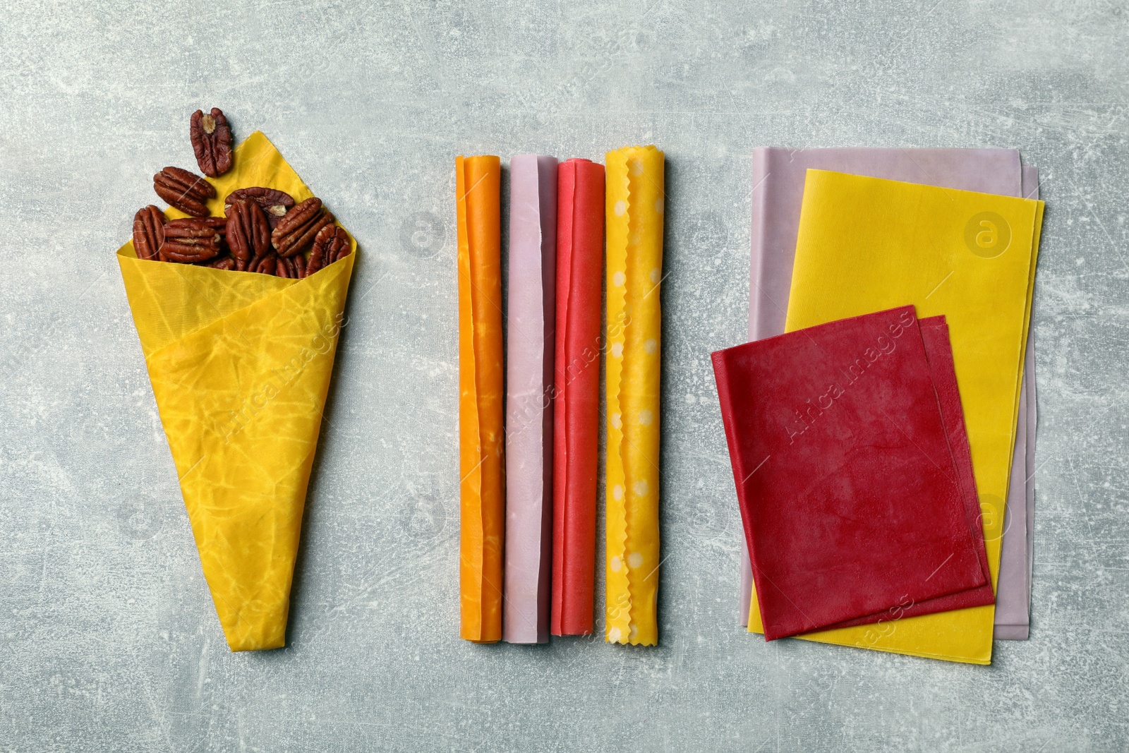 Photo of Flat lay composition with colorful beeswax food wraps and nuts on grey table
