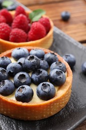 Photo of Tartlet with fresh blueberries on slate plate, closeup. Delicious dessert