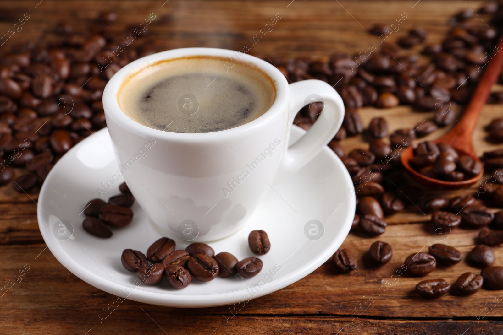 Image of Steaming coffee in cup and roasted beans on wooden table