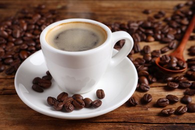 Image of Steaming coffee in cup and roasted beans on wooden table