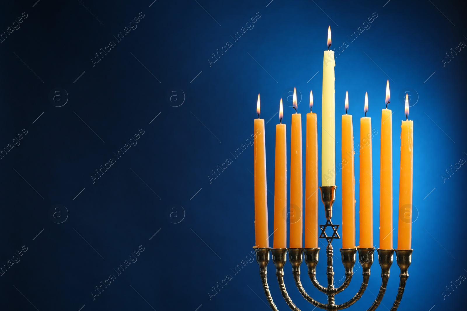 Photo of Hanukkah celebration. Menorah with burning candles on blue background, space for text