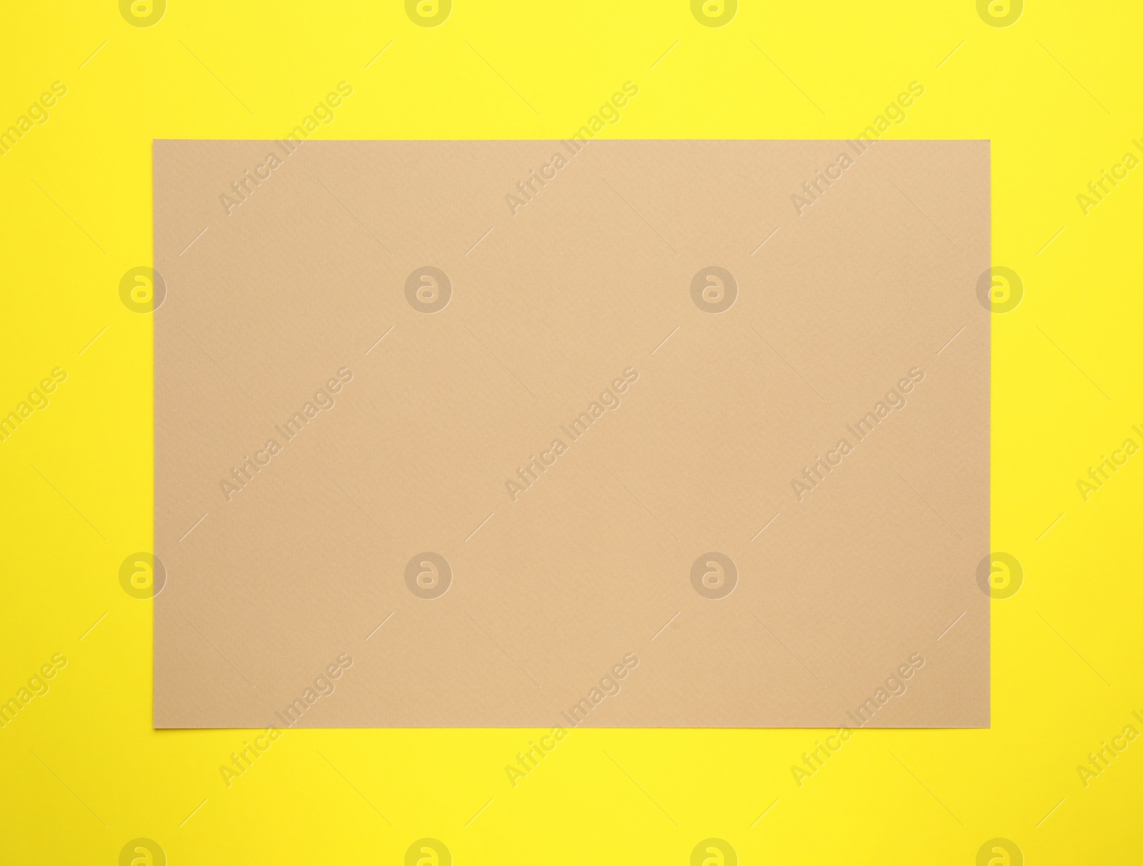 Photo of Sheet of brown paper on yellow background, top view