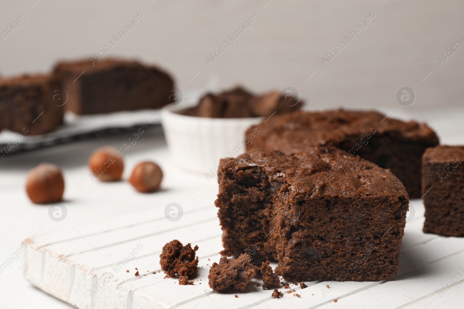 Photo of Board with fresh brownies on table against light background, space for text. Delicious chocolate pie