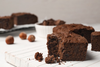 Photo of Board with fresh brownies on table against light background, space for text. Delicious chocolate pie