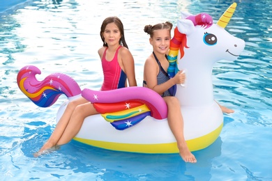 Photo of Happy girls on inflatable unicorn in swimming pool