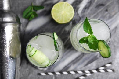 Photo of Glasses of refreshing cucumber water with ice grey on table, flat lay