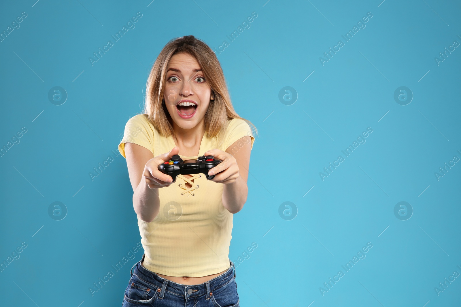 Photo of Emotional young woman playing video games with controller on color background. Space for text