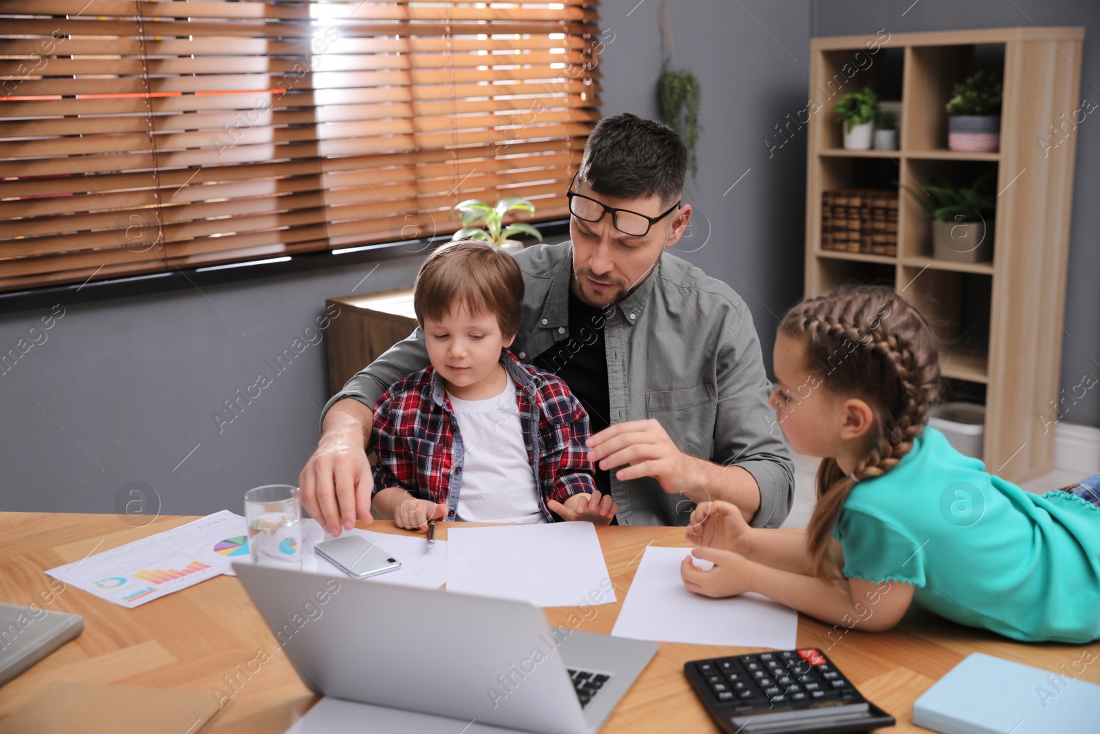 Photo of Overwhelmed man combining parenting and work at home