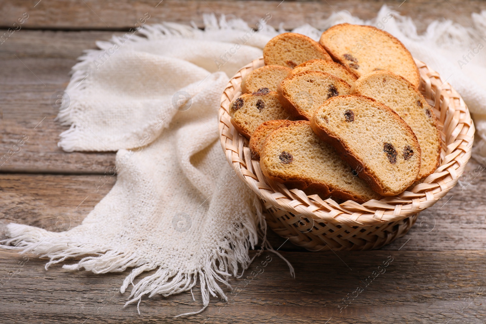 Photo of Sweet hard chuck crackers with raisins in wicker basket on wooden table. Space for text