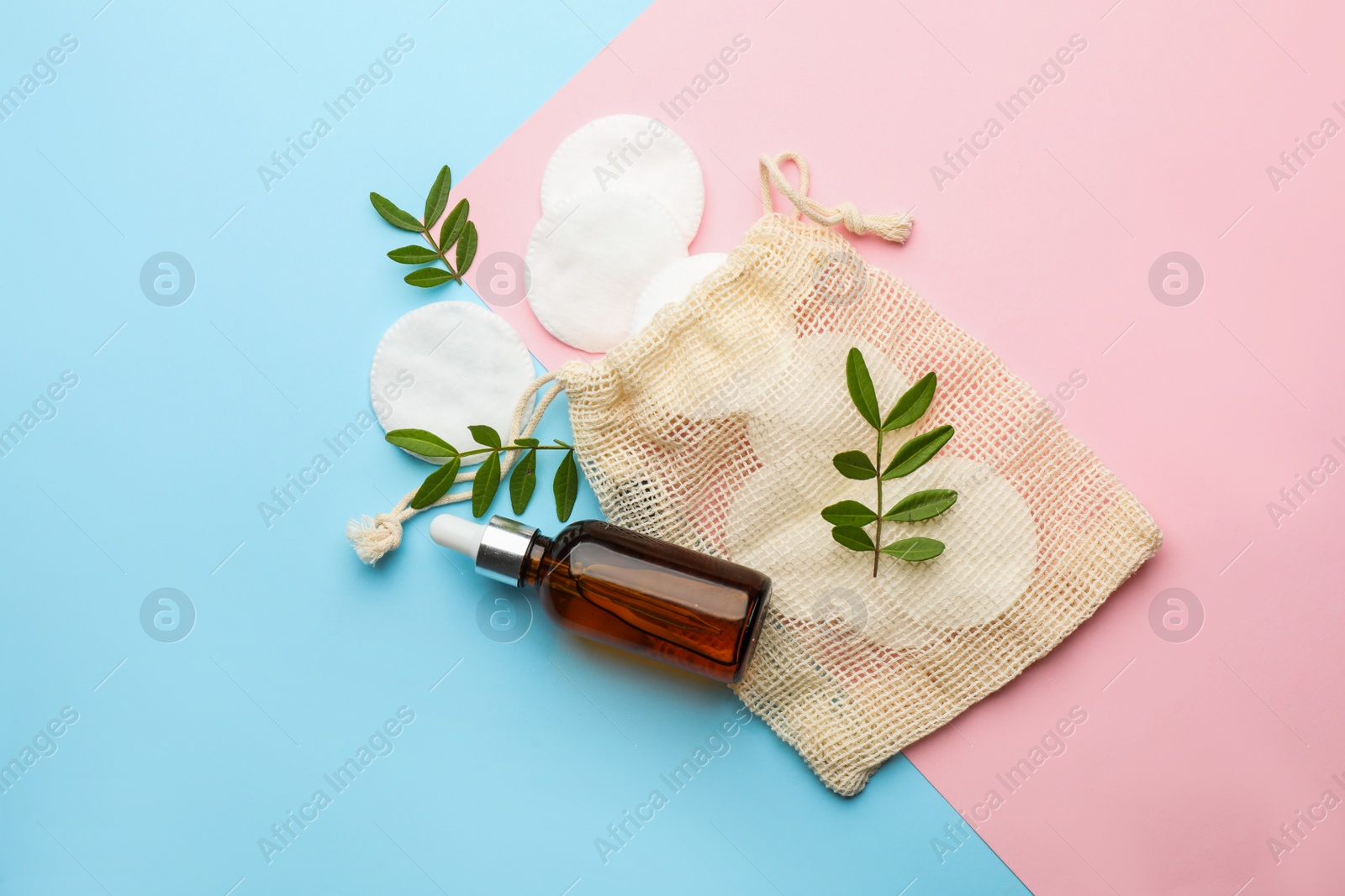 Photo of Cotton pads, leaves and makeup removal product on color background, flat lay