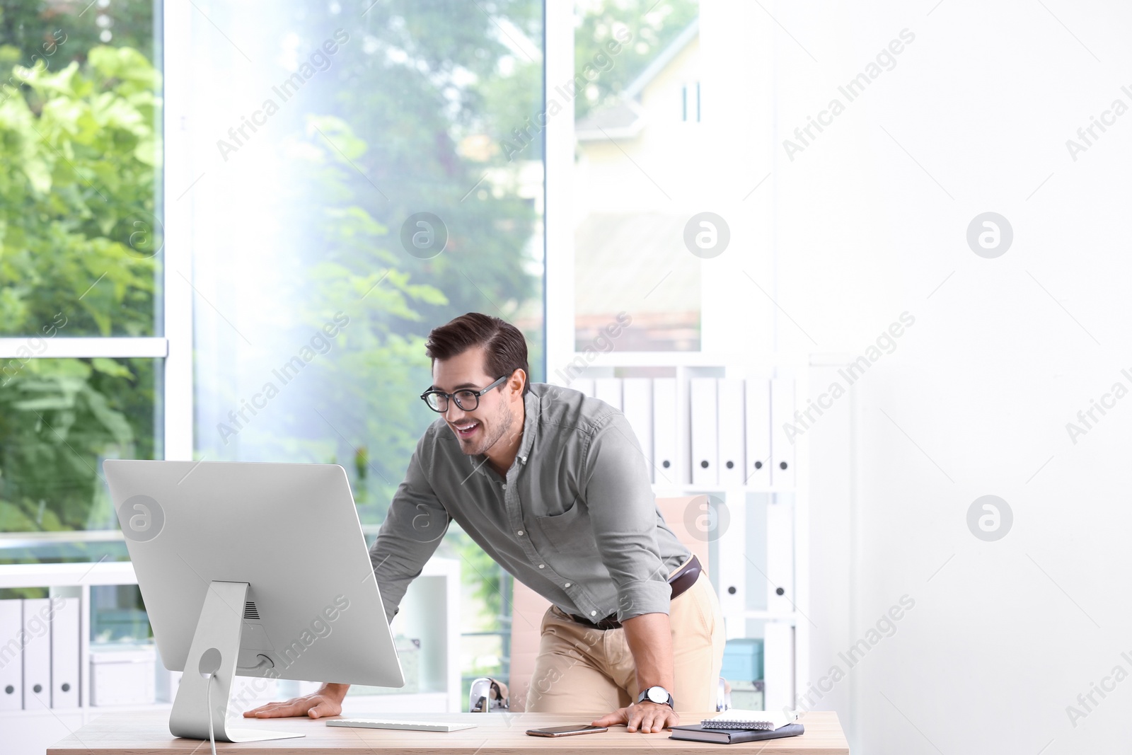 Photo of Handsome young man working with computer in office