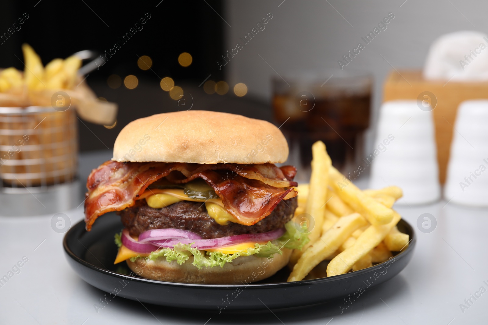 Photo of Tasty burger with bacon, vegetables and patty served with french fries on light grey table, closeup