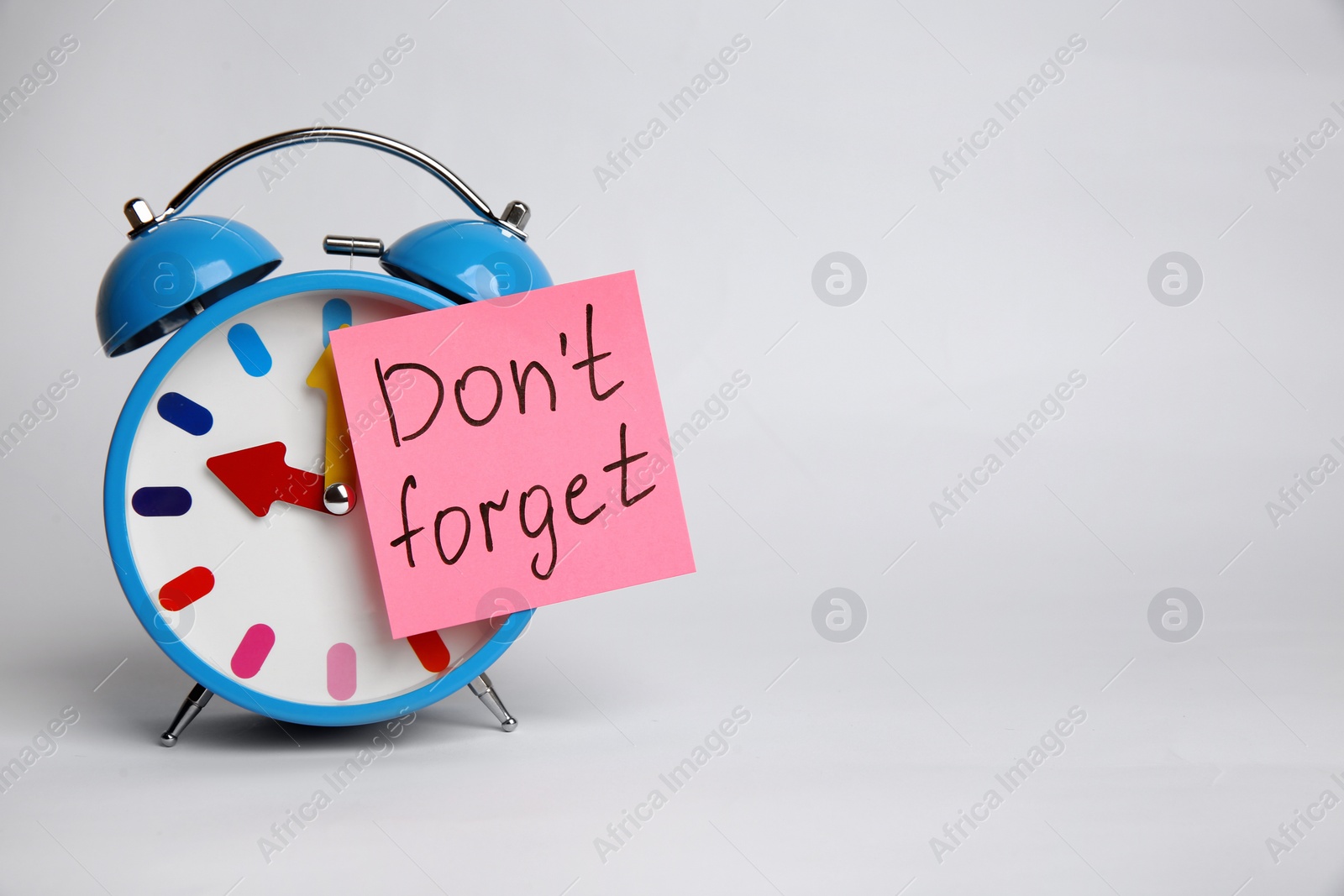 Photo of Alarm clock and reminder note with text Don't forget on light grey background. Space for design