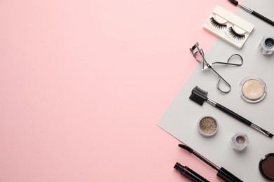 Photo of Flat lay composition with eyelash curler, makeup products and accessories on pink background. Space for text