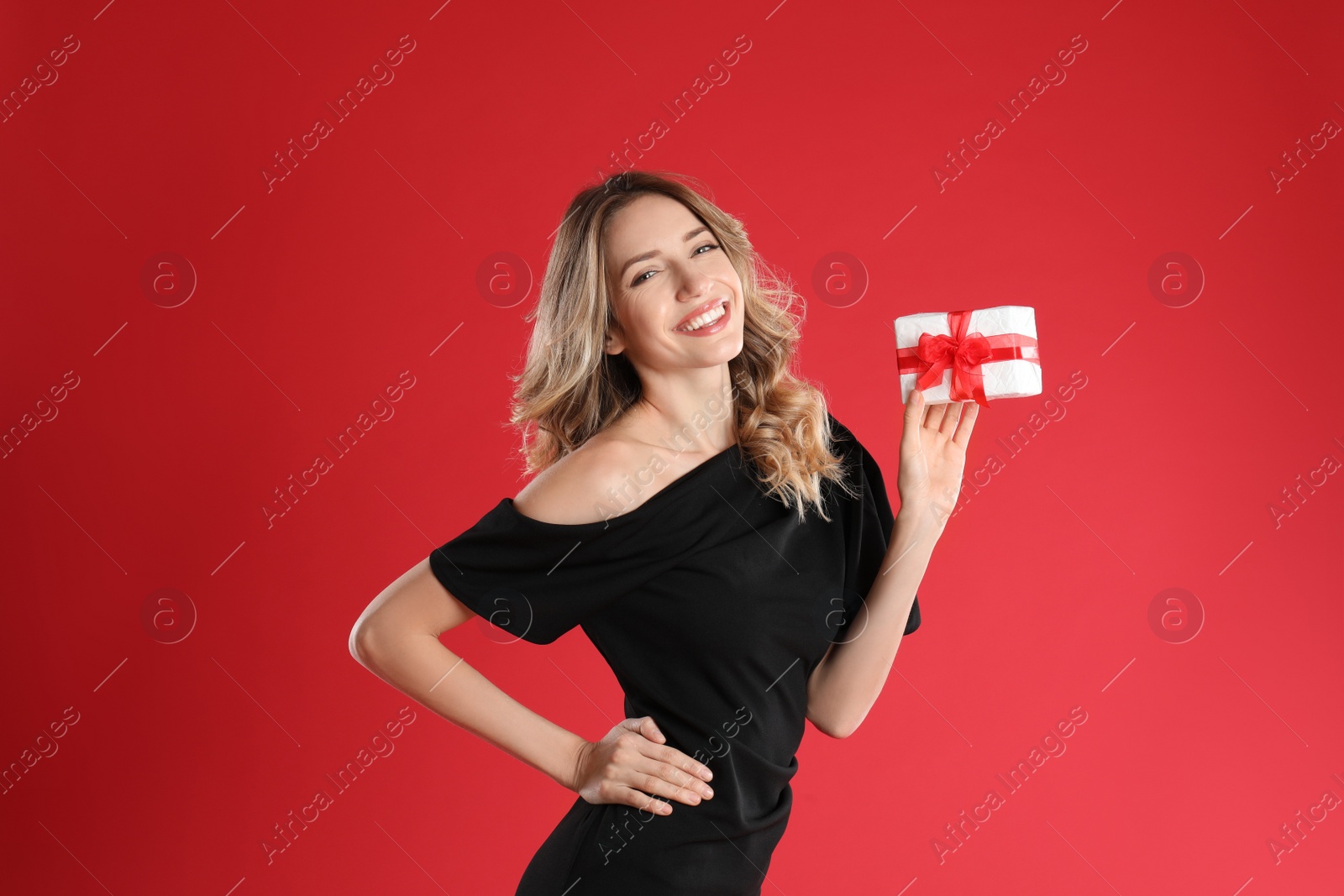 Photo of Beautiful young woman with Christmas present on red background