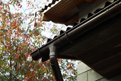 Rain gutter system with drainpipe on house outdoors, low angle view