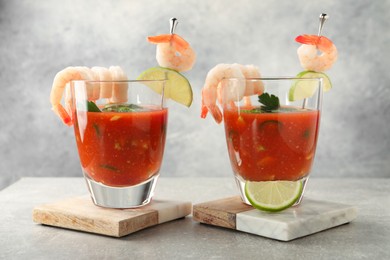 Tasty shrimp cocktail with sauce in glasses and lime on light grey table, closeup