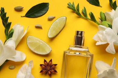 Flat lay composition with bottle of perfume and fresh citrus fruits on yellow background