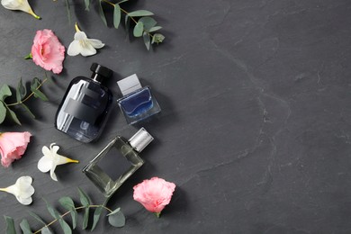 Luxury perfumes and floral decor on black table, flat lay. Space for text