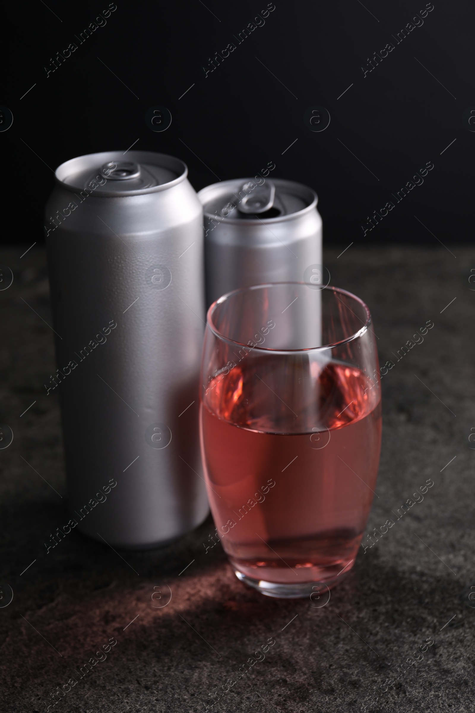 Photo of Energy drink in glass and aluminium cans on grey table