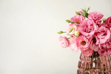 Photo of Beautiful pink Eustoma flowers in vase on light background. Space for text