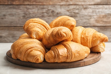 Wooden board with tasty croissants on table