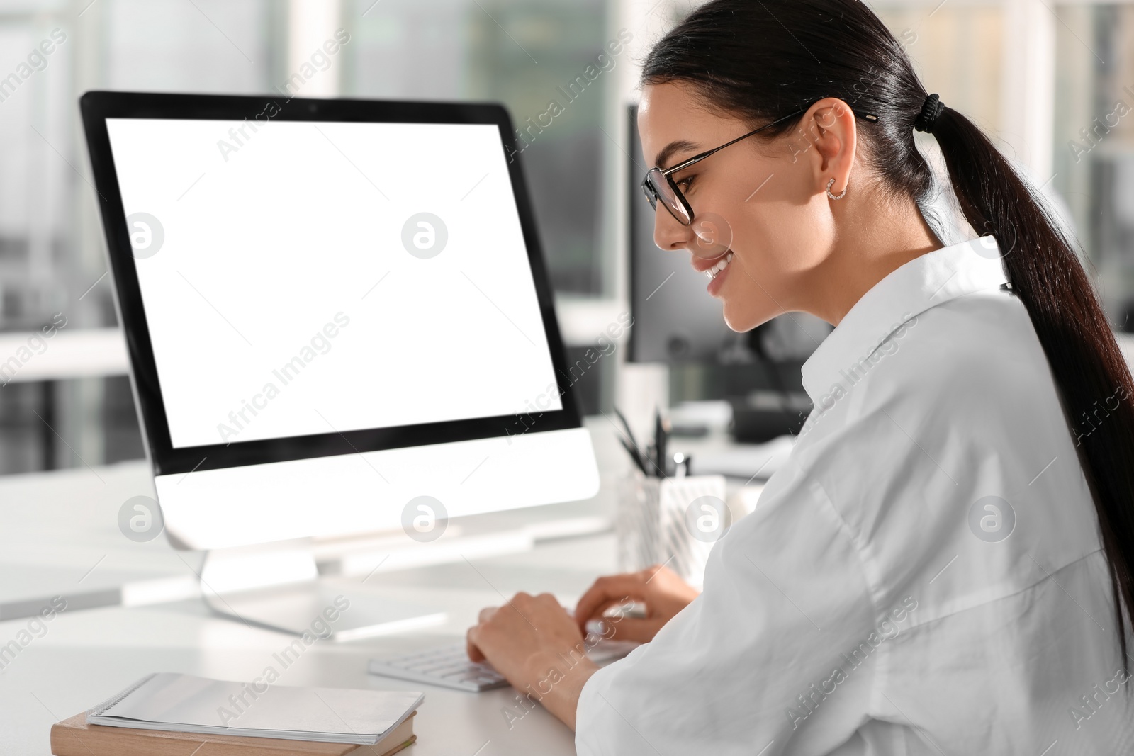 Photo of Happy woman using modern computer at white desk in office