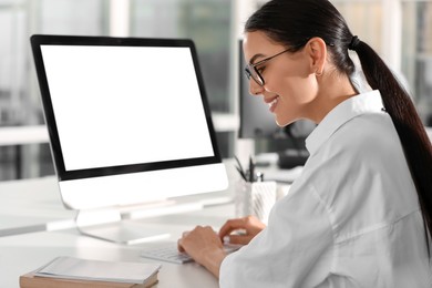 Photo of Happy woman using modern computer at white desk in office