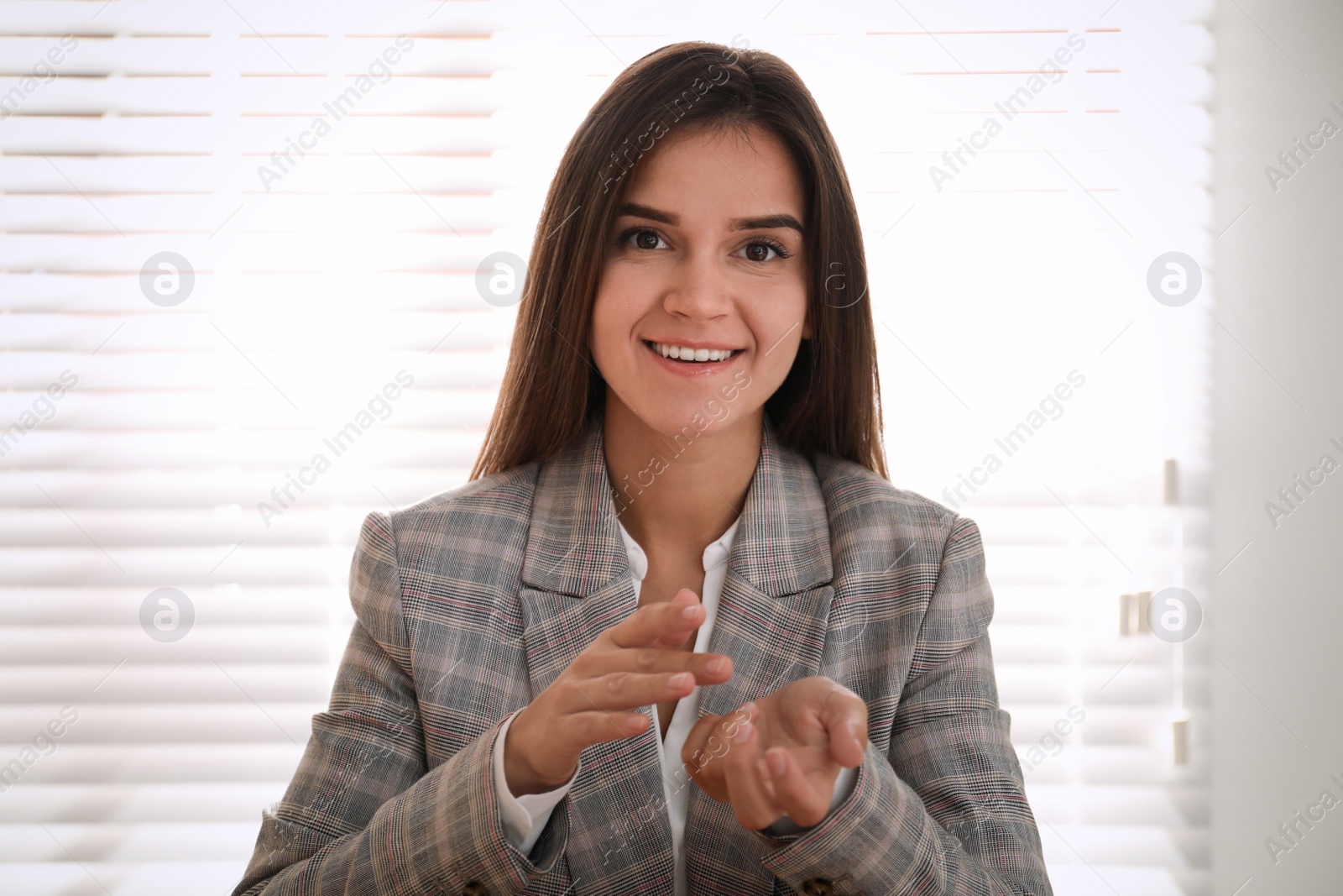 Photo of Young woman talking to her coworkers through video conference in office, view from webcam