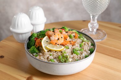 Photo of Tasty rice with shrimps and vegetables in bowl on wooden table