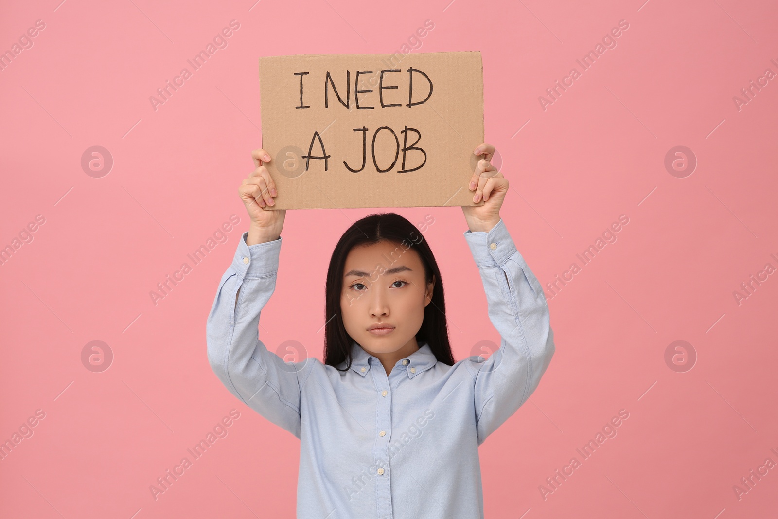 Photo of Unemployed Asian woman holding sign with phrase I Need A Job on pink background