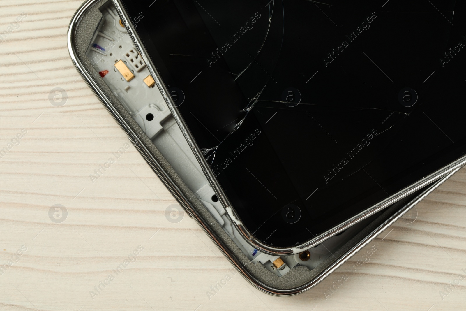 Photo of Broken smartphone on light beige wooden background, closeup. Device repair