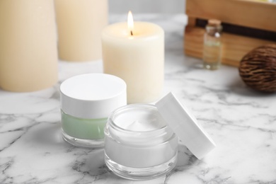 Photo of Jars of facial cream on white marble table