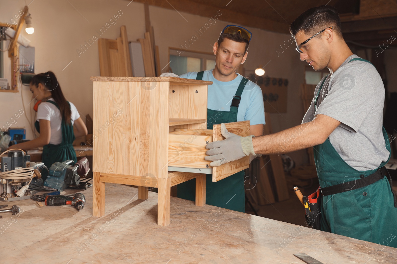 Photo of Professional carpenters assembling wooden cabinet in workshop