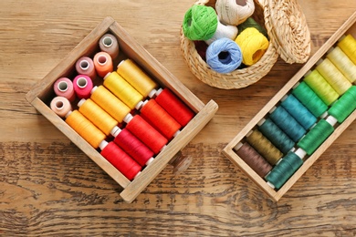 Photo of Containers with set of color sewing threads on wooden background