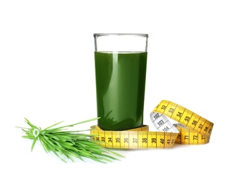 Glass of spirulina drink, measuring tape and wheat grass on white background