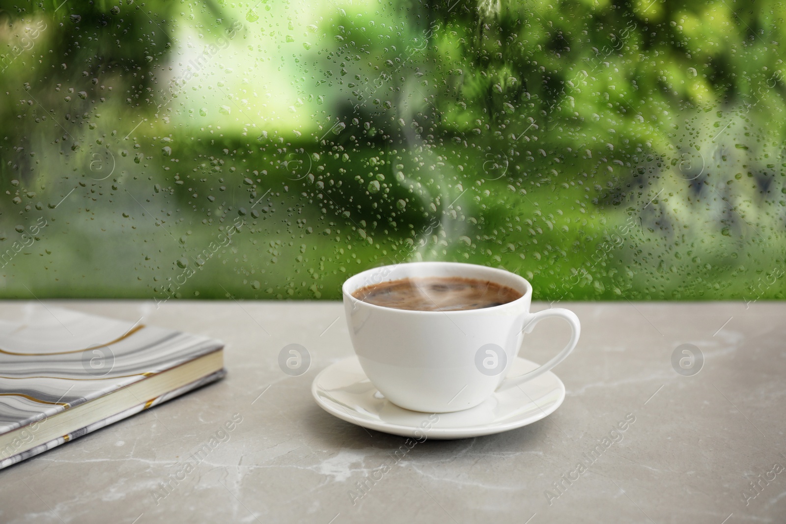 Image of Cup of hot drink near window on rainy day