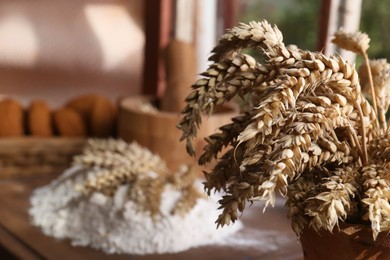 Photo of Wheat spikes against blurred background indoors, closeup. Space for text