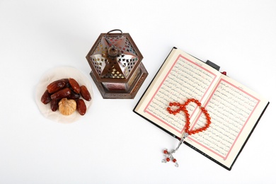 Photo of Muslim lamp, dates, Koran and prayer beads on white background, top view