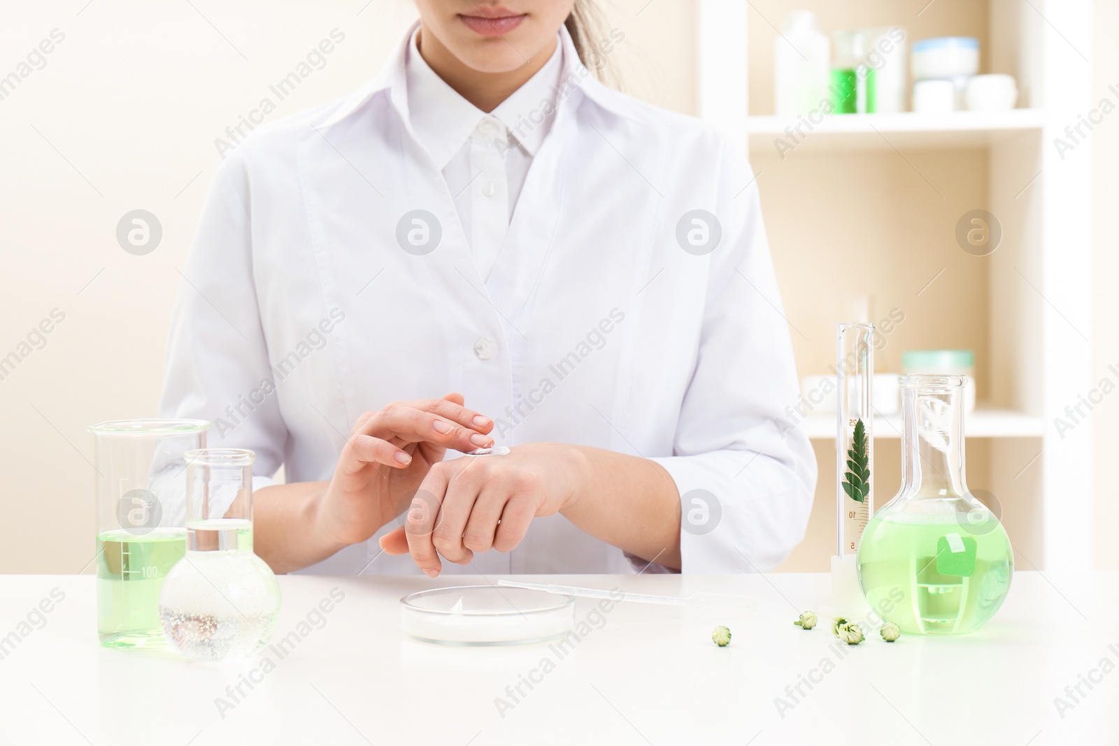 Photo of Female dermatologist testing skin care product at table, closeup