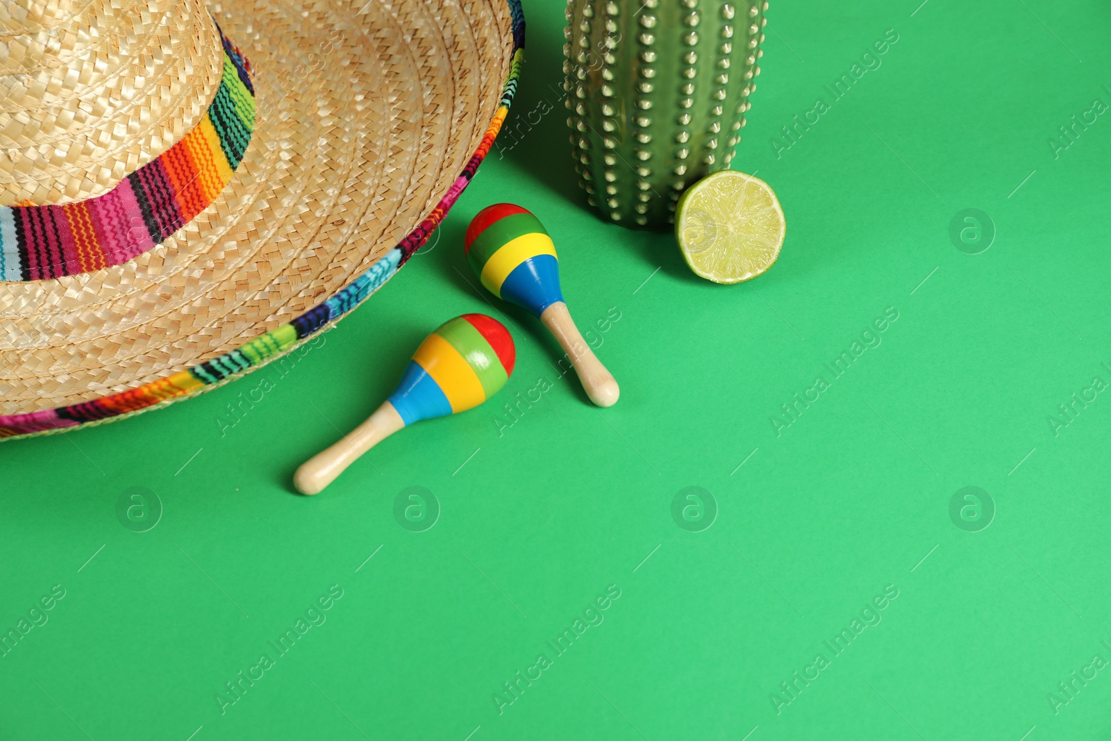 Photo of Composition with Mexican sombrero hat and maracas on green table, above view. Space for text