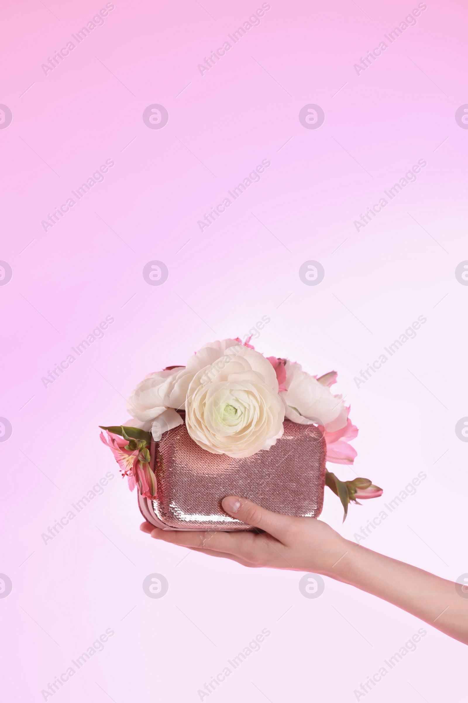 Photo of Woman holding elegant handbag with spring flowers on pink background, closeup. Space for text