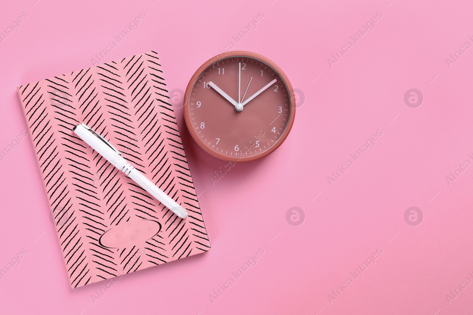 Photo of Clock and planner with pen on colorful background, flat lay. Space for text