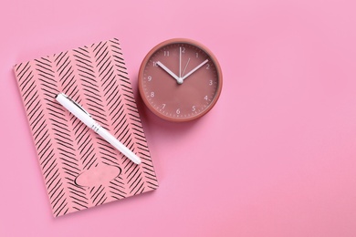 Photo of Clock and planner with pen on colorful background, flat lay. Space for text