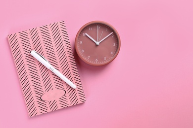 Clock and planner with pen on colorful background, flat lay. Space for text