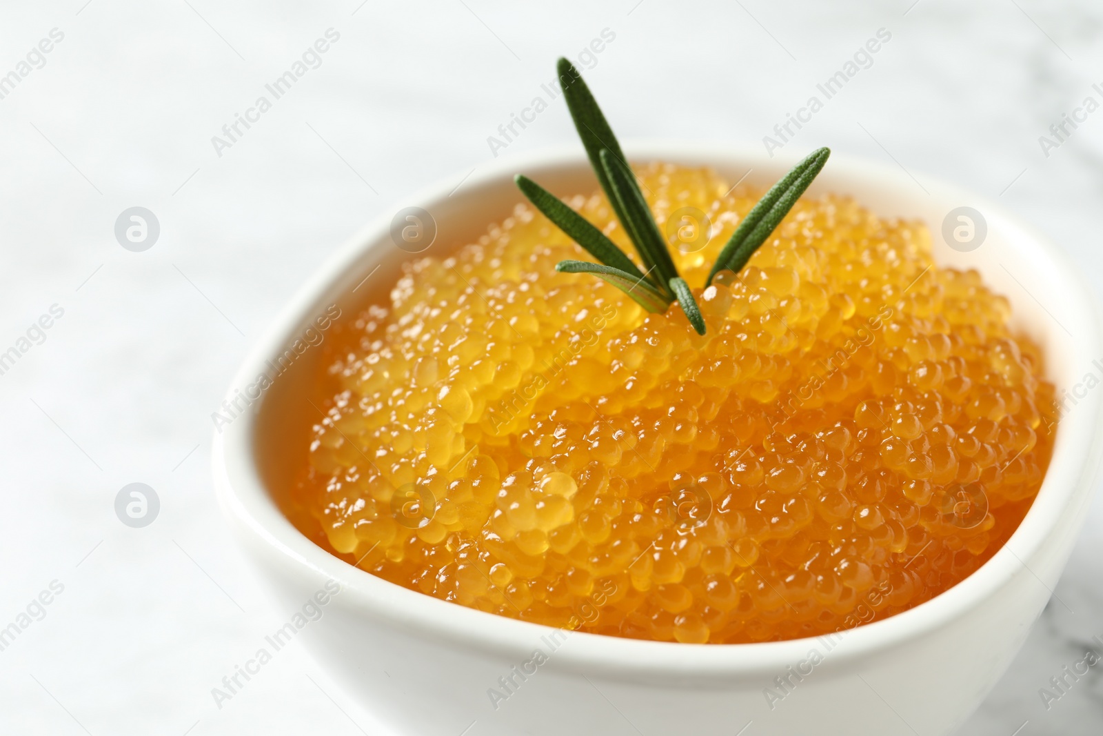 Photo of Fresh pike caviar and rosemary in bowl on white table, closeup