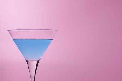 Martini glass with delicious cocktail on pink background, space for text